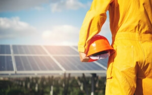 Solar employee holding their helmet, facing a solar panel.