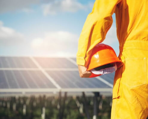 Solar employee holding their helmet, facing a solar panel.