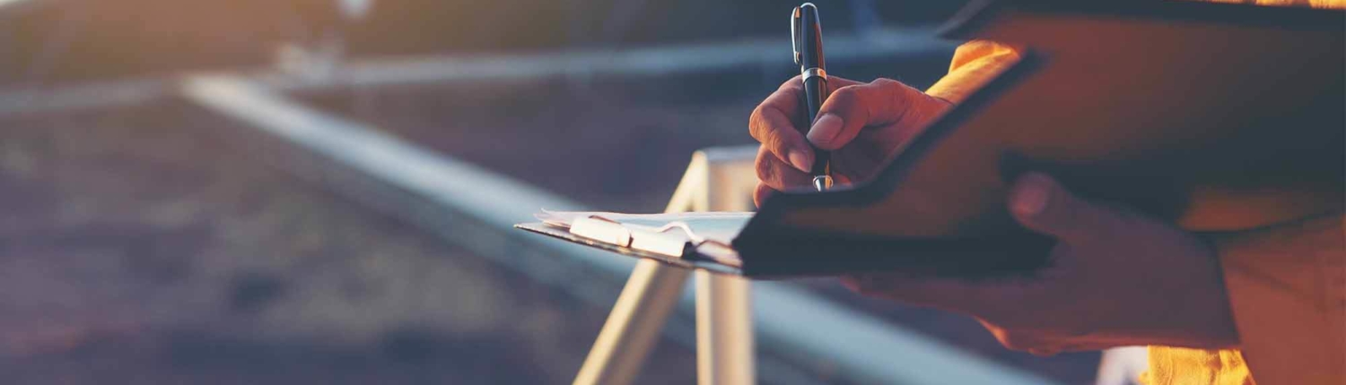 Person writing in a notepad in an empty field